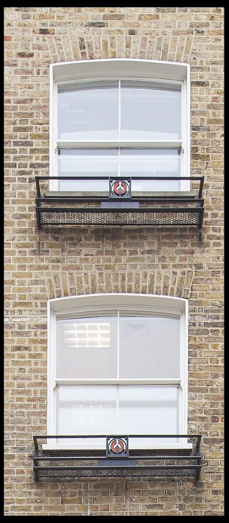 Two Victorian four-paned windows with iron window box supports