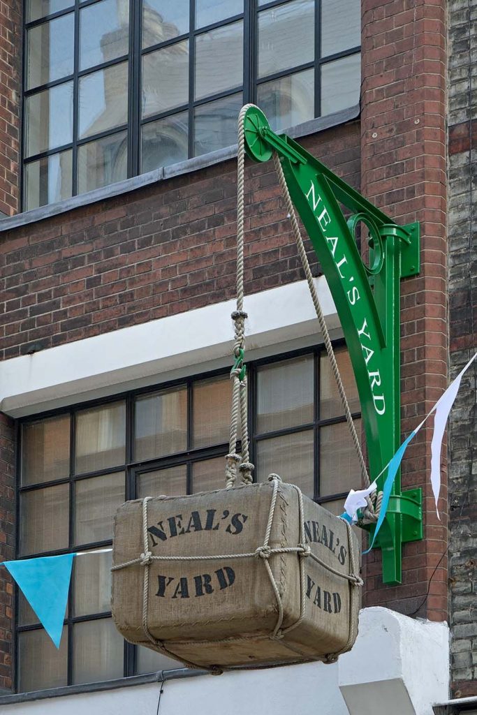 Green iron hoist supporting hessian bale as signage for Neal’s Yard