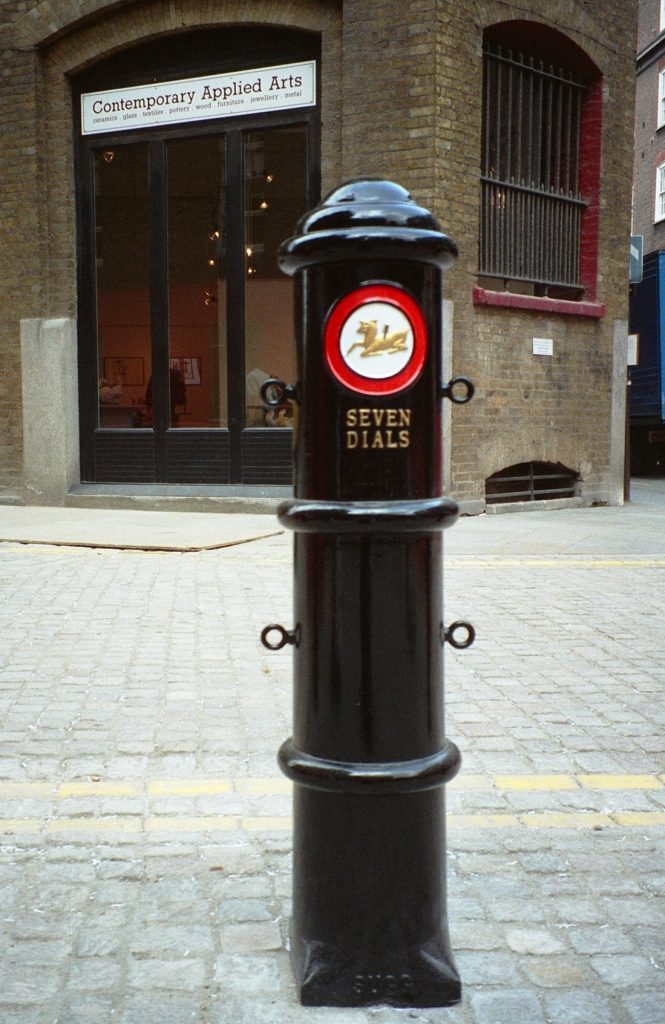 Bespoke Seven Dials bollard. Painted black, with Seven Dials raised in gold and the Golden Hind motif painted in gold, red and white.